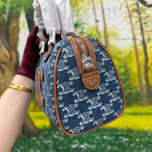 Celine Triomphe handväska i jeans - Säljer en snygg Celine handväska i blått jeanstyg med vitt mönster och bruna skinn-detaljer. Väskan har Celines ikoniska Triomphe-logo framtill, silverfärgad dragkedja och två handtag. Perfekt storlek för det viktigaste och ger en cool vibe till din outfit.