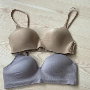 2 mjuka linnetoppar från Lindex , 80B - Två bekväma linnetoppar från Lindex i storlek 80B. En i beige och en i ljuslila, båda med justerbara axelband och vadderade kupor. Snyggt sömlös design och bred resår under bysten för extra stöd. Perfekta för en chill och enkel look.