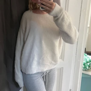 Fluffig vit stickad tröja - Supermjuk och fluffig vit stickad tröja med rund hals och långa ärmar. Perfekt för lager-på-lager och ger en chill vibe till din outfit. Oversized passform för extra mysfaktor💕
