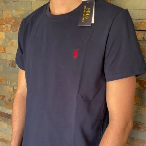 Polo Ralph Lauren T-shirt - Jag säljer en riktigt snygg blå polo Ralph lauren T-shirt. Denna T-shirt är väldigt välkänd och många som letar efter den. Skicket på denna är helt nytt, alltså 10/10. Storleken är M. Priset jag kommer sälja denna för är 399kr men kan sänka priset vid snabb affär. Kom med prisförslag. Kontakta mig vid några funderingar eller frågor. MVH