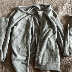 Grå kofta från Gina Tricot - Mysig grå kofta från Gina Tricot i storlek S. Klassisk modell med rund halsringning och knappar hela vägen framtill. Långärmad och i mjukt, tunt material som passar perfekt till lager-på-lager. Enkel att matcha med allt i garderoben.