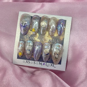 Xavier (L);Medium Almond - Set med press-on naglar i lila och silverglittrig design. Naglarna har söta anime (Xavier), stjärnor, rosetter och blommor som dekoration. Perfekt för dig som vill ha en unik och lekfull look. Kommer i L: 17 mm, 12,5 mm, 13 mm, 12 mm, 10 mm 