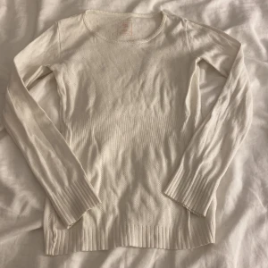 Vit tröja  - Supersöt vit tröja med diskret hålmönster och breda ribbade muddar vid ärmslut och nederkant. Rund halsringning och långärmad.