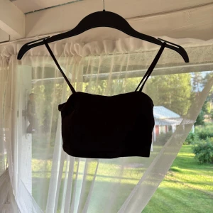 Svart croppad linne från H&M Divided - Svart croppad linne från H&M Divided med tunna axelband. Enkel och stilren design som passar perfekt till jeans eller kjol. Mjuk och bekväm, perfekt för varma dagar eller lager på lager.