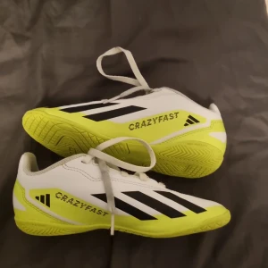 Adidas Crazyfast vita fotbollsskor - Säljer ett par Adidas Crazyfast fotbollsskor i storlek 32. Skorna är vita med neon-gula detaljer och svarta ränder på sidorna. De har snörning och en platt sula som är perfekt för inomhusspel. Materialet är syntet med meshfoder för extra komfort. Pris kan diskuteras skriv vid minsta fundering😊