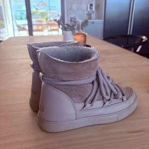 Beige vinterboots från Inuikii - Snygga beige vinterboots från Inuikii med mjuk fårullsfoder, mocka och skinn på utsidan. Grova snören och högre skaft. Säljer eftersom jag ska köpa nya.