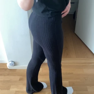 Svarta ribbade byxor från SHEIN - Svarta ribbade byxor från SHEIN i storlek S. Byxorna är högmidjade med utsvängda ben och har en mjuk, stickad känsla. Perfekta för en chill och trendig look. Snygga att styla med en crop top eller hoodie.