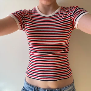 Randig croppad topp  - Säljer en croppad topp från H&M Divided i storlek XXS. Den har ett snyggt randigt mönster i rött, marinblått och vitt, med rund hals och korta ärmar. Materialet är mjuk bomull som sitter tight och bekvämt❤️🫐xoxo