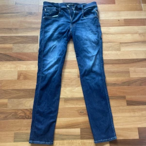 Replay Anbass jeans mörkblå - Snygga mörkblå jeans från Replay, modell Anbass. Slim fit med klassisk femficksdesign och snygga kontrastsömmar. Jeansen har en stilren look och är tillverkade i stretchig denim för extra komfort.