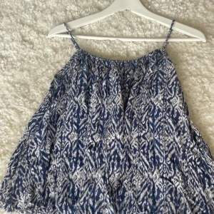 Blåvit mönstrad linnetopp Soul River - Säljer en luftig blåvit linnetopp från Soul River i storlek XS. Toppen har tunna axelband och ett snyggt abstrakt mönster i blått och vitt. Perfekt för varma dagar och enkel att matcha med jeans eller shorts.