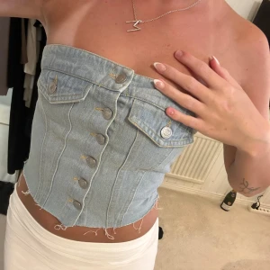 Ljusblå jeans tubtopp med knappar - Säljer en snygg ljusblå tubtopp i jeans med silverfärgade knappar framtill 🥰