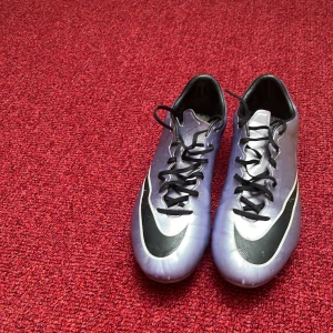Silvriga Nike fotbollsskor med svarta detaljer - Säljer ett par grymma silvriga Nike fotbollsskor med svarta snören. Skorna är från 2015/16 säsongen. 
