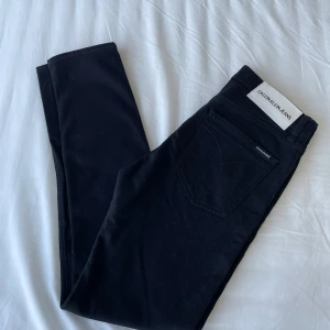 Calvin Klein jeans - Svarta jeans från Calvin Klein med klassisk femficksdesign och silverfärgade nitar. Snyggt broderade bakfickor och tydlig logotyp på bakre etiketten. Jeansen är i stretchigt material storlek 31/32.