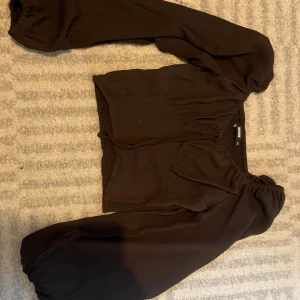 Blus med puffärmar - Säljer en brun blus från bikbok med urringning och stora puffärmar. Toppen har resår vid axlar och ärmslut för en snygg passform. Skriv innan du köper! 
