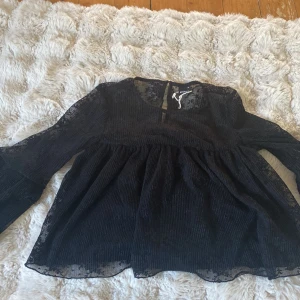 Svart blus med volangärmar - Säljer en svart blus från Gina Tricot med fint mönster och spets upp till och volanger på ärmarna. Har bara använt 2 gånger🤍💕