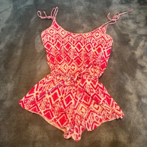 Rosa mönstrad playsuit - Superfin mörkrosa och vit mönstrad playsuit från Crocker och ger en snygg passform med justerbara snören. Perfekt för en varm sommar då den är luftig🥰