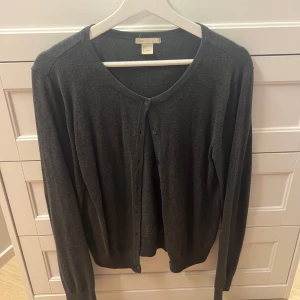 Mörkgrå kofta från Boomerang - Mysig mörkgrå kofta från hm i mjuk ullblandning. Klassisk rund halsringning, långa ärmar och knäppning framtill med små knappar. Perfekt att slänga över en t-shirt eller linne för en chill look.