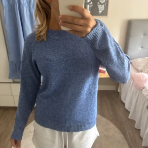 Blå stickad tröja från Vero Moda - Mysig blå stickad tröja från Vero Moda med rund hals och ribbade muddar vid ärmslut och nederkant. Tröjan har en enkel, klassisk design och är perfekt för att hålla dig varm under kyliga dagar. Passar dig som gillar en chill och stilren look.