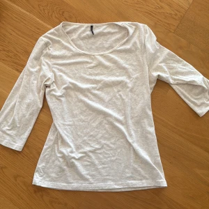 Beige topp med trekvartsärm - En enkel och fräsch vit topp från H&M med rund halsringning och trekvartsärm. Tillverkad i mjuk bomull som känns skön mot huden. Perfekt att matcha med jeans eller kjol för en clean och chill look.