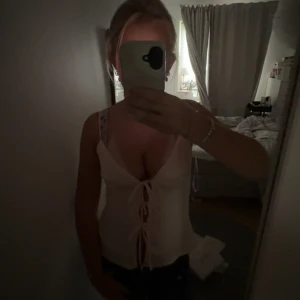 ljusrosa linnetopp med snörning framtill - Säljer en ljusrosa linnetopp med djup v-ringning och snygg snörning framtill. Toppen är ärmlös med smala axelband och har en figurnära passform som framhäver siluetten. Perfekt för varma dagar och att styla med jeans eller kjol. Liten i storleken. Aldrig använt.