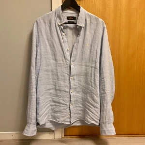 Ljusblå - linneskjorta Morris - Snygg ljusblå skjorta från Morris i 100% linne. Button down-krage och lång ärm. Perfekt för dig som gillar en stilren och luftig look.                                                         Storlek: M                                                                              Skick: 10/10                                                                          Nytt pris: Ca 1299kr                                                            ❗️Kontakta mig vid minsta lilla fråga❗️