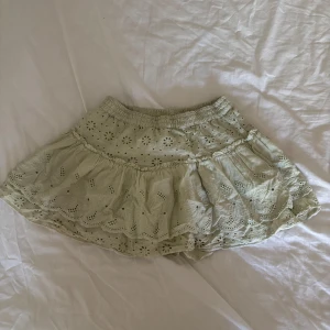 Ljusgrön  broderad kjol från Zara - Supersöt ljusgrön kortkjol från Zara med broderade blommor och volangkant. Kjolen har resår i midjan och är gjord i mjuk bomull, perfekt för dig som gillar romantisk och chill stil. Passar dig som vill ha något extra gulligt i garderoben. Kjolen har shorts under 