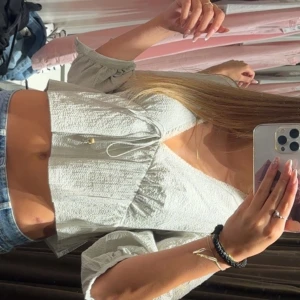 Ljusgrå croppad blus med knyt - Superfin ljusgrøn croppad blus med v-ringning och knyt framtill. Blusen har trekvartsärmar med volangkant och är gjord i ett lätt, strukturerat tyg som känns luftigt. 