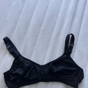Svart BH från Åhléns - Svart BH från Åhléns utan vadd. Justerbara axelband och klassisk siluett med mjuka kupor. Vid frågor hör av dig!