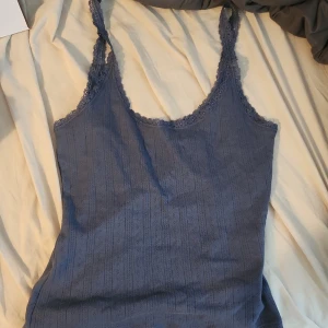 Blå spetskantad linnetopp 157 - Supersöt blå linnetopp från 157. Toppen har smala axelband och fina spetsdetaljer längs kanterna. Materialet är ribbat med diskret mönster som ger en extra touch. Perfekt för att styla lager på lager eller till jeansshorts. Köpt på vinted. Säljer för den var förstor. Det står xs men den va lite förstor på mig som normalt har S. Rekommenderas för S-M.