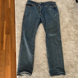 Levi's 514 blå jeans W32 L32 - Klassiska blå Levi's 514 jeans med rak passform och normal midja. Jeansen är i denim med snygga kontrastsömmar och femficksdesign. Perfekta för dig som gillar en tidlös och avslappnad stil.