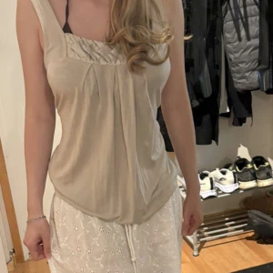 Beige linnetopp med veckad detalj - Supersnygg beige linnetopp med breda axelband och unik veckad detalj upptill. Toppen har en lös passform och är tillverkad i mjukt, lätt material som känns skönt mot huden. Perfekt för varma dagar och enkel att styla med dina favoritjeans eller kjol. Storlek M-L o kan även bli som en kort klänning. Används inte. O väldigt sparsamt använd. 