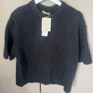 Svart stickad topp från Gina tricot medium  - Stickad kortärmad topp från Gina tricot . Tröjan är ny med lappar .  korta ärmar och rund halsringning. Tröjan har en lite lös passform och är gjord i ett mjukt material 