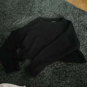 Svart croppad stickad tröja från Even&Odd - Säljer en svart croppad stickad tröja från Even&Odd. Tröjan har lång ärm och rund halsringning, perfekt för lager-på-lager eller till jeans. Enkel och stilren design som passar till mycket.