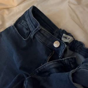 Mörkblå bootcut jeans från ONLY - Säljer ett par mörkblå jeans från ONLY med bootcut-modell. Jeansen har klassisk femficksdesign, dragkedja och knapp framtill samt bälteshällor. Perfekta för dig som gillar en tidlös och snygg look - plick. Jag säljer dem för att jag inte har någon användning för dem 😊