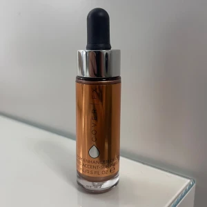 Cover FX Custom Enhancer Drops Candlelight - Flytande highlighter från Cover FX i nyansen Candlelight. Kommer i en glasflaska med pipett och har en metallisk, varm bronsig ton som ger glow till huden. Perfekt för att blanda i foundation eller applicera direkt på kindbenen. Helt oanvänd. 