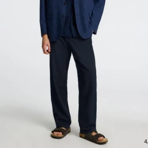 Marinblåa linnebyxor med snörning - Snygga marinblåa linnebyxor från Selected med avslappnad passform och snörning i midjan. Byxorna har sidofickor fram och bakfickor med knappar. Perfekta för en stilren och bekväm look.