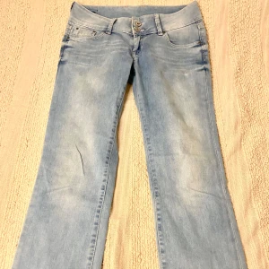 Ljusblå lågmidjade Pepe Jeans - Säljer ett par ljusblå lågmidjade Pepe Jeans med klassisk femficksdesign och raka ben. Byxorna har dubbla knappar i midjan och diskreta sömmar på bakfickorna. Perfekta för en avslappnad stil.