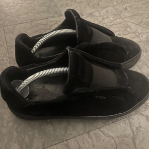 Axel arigato skor - Säljer ett par svarta sneakers från ARIGATO med stilren design. Skorna har rund tå, platt sula och är tillverkade i mocka och syntet. Perfekta för dig som gillar minimalistisk stil.