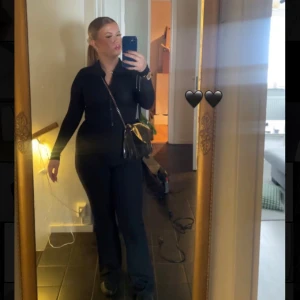 Svart jumpsuit med dragkedja och krage - Säljer en svart långärmad jumpsuit med dragkedja framtill och klassisk krage. Tight passform som framhäver figuren och långa ben. Perfekt för en trendig och stilren look.