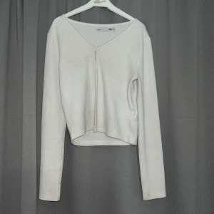 Vit ribbad kofta  - Säljer en vit ribbad kofta från lager 157 och en knapp framtill. Koftan har lång ärm och är något croppad i modellen. Perfekt att slänga över en topp för en enkel och stilren look.