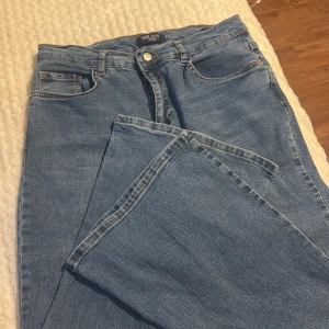 Blå jeansbyxor med normal passform - Klassiska blå jeansbyxor med fem fickor och normal passform. Byxorna har raka ben och bälteshällor i midjan. Perfekta för en avslappnad stil och passar till det mesta i garderoben.