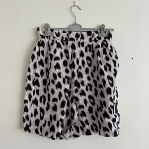 Leopardmönstrade shorts med fickor - Säljer ett par snygga shorts med svartvitt leopardmönster. Shortsen har hög midja, resår baktill och stora fickor. 100% linne. Saknar ett bälte, i övrigt utan anmärkningar! 