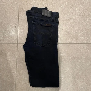 Marinblåa nudie jeans - Säljer ett par marinblåa jeans från Nudie Jeans med klassisk femficksdesign och svarta sömmar. Jeansen har normal passform och är tillverkade i ett mjukt denimtyg. Perfekta för dig som gillar stilrena och tidlösa byxor. Dem är i fint skick och sitter bra på dig som är runt 180-187! Skriv vid eventuella frågor!