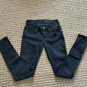Svarta jeans från Tiger of Sweden - Säljer ett par svarta jeans från Tiger of Sweden i modellen Slender. Jeansen har fem fickor, smal passform och klassisk design med knapp och dragkedja. Perfekta för dig som gillar stilrena och tajta jeans.