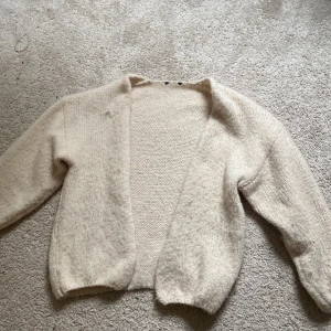 Beige stickad kofta - Mysig beige stickad kofta med lång ärm och öppen framtill❤️säljer den för den är förkort i ärmarna på mig, använd bara 1 gång den är som ny❤️buda gärna