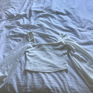 Vit långärmad topp med fyrkantig urringning - Säljer en stilren vit topp med lång ärm och snygg fyrkantig urringning. Perfekt att matcha med jeans eller kjol för en trendig look.