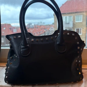 Svart axelväska med nitar - svart väska med nitar på, extremt mycket utrymme och med ett justerbart band och en stor necessär som kommer med den men också kan användas till en innerväska. små slitningar som visas på bilden annars i bra form🩷