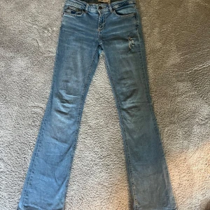Low waist bootcut jeans - Ljusblå bootcut jeans med låg midja och coola hål vid låret och ens bakfickan