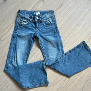 Blå jeansbyxor från Gina Tricot - Säljer ett par klassiska blå jeansbyxor från Gina Tricot i storlek 146. Byxorna har normal passform, raka ben och femficksdesign med silverfärgade knappar. Perfekta till vardags för en avslappnad stil.