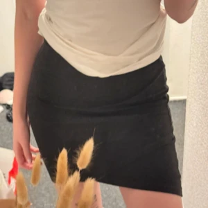 Svart ribbad kortkjol från Gina Tricot - Säljer en svart ribbad kortkjol från Gina Tricot. Kjolen har en tight passform och är tillverkad i ett stretchigt material som sitter snyggt på kroppen. Perfekt att matcha med en enkel topp eller stickad tröja.